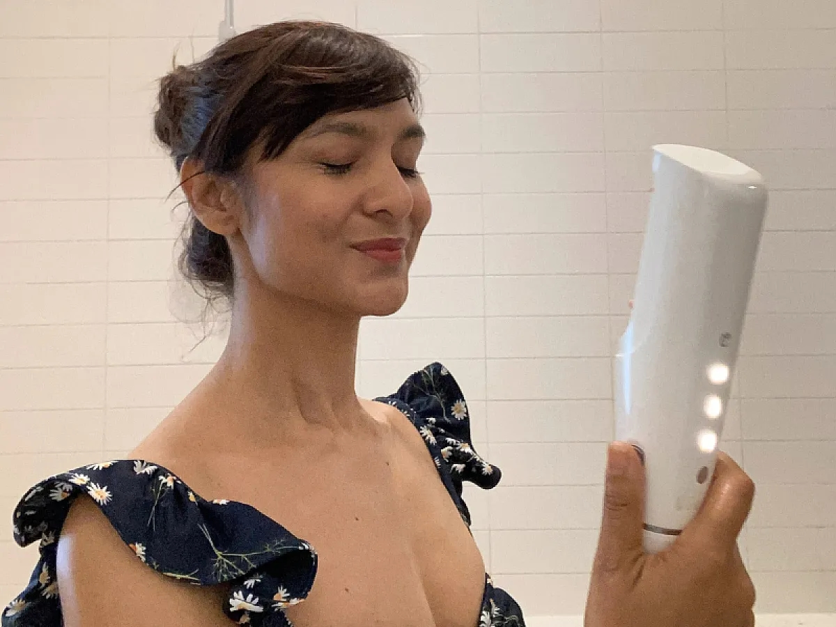 Frau versprüht Sonnenschutz mit Hilfe des ONE von IONIQ Skincare im Gesicht