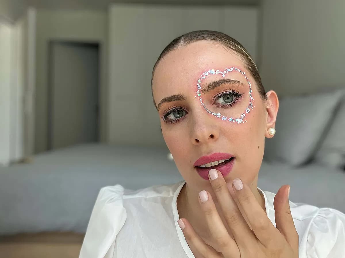 Frau tupft farbigen Lipbalm auf ihr Lippen